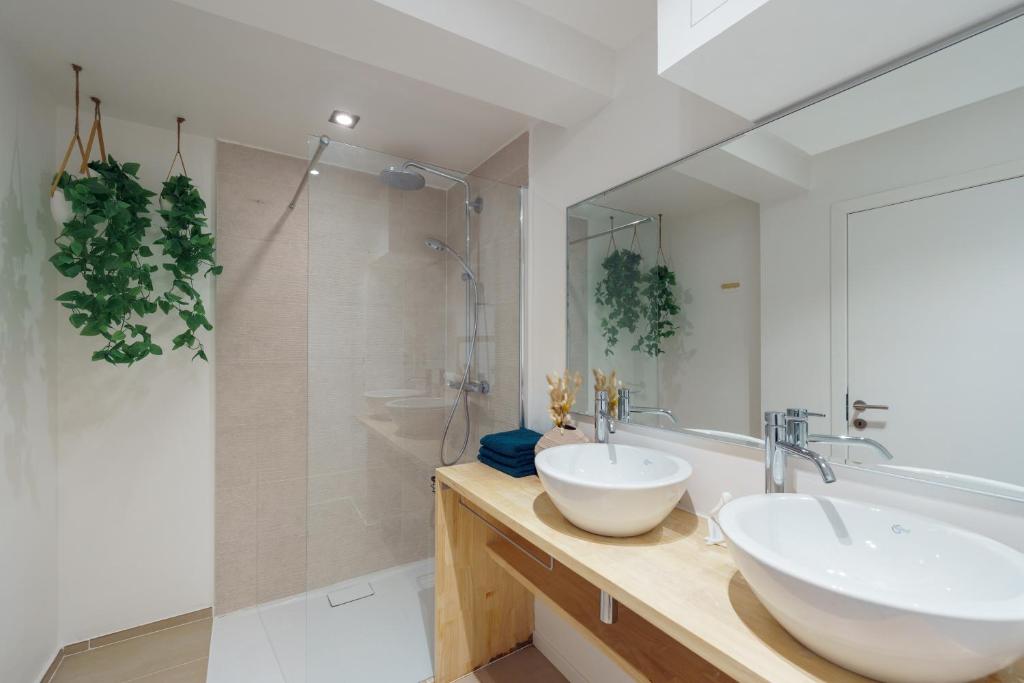 een badkamer met 2 wastafels, een bad en een spiegel bij ZILTE STILTE in Oostende
