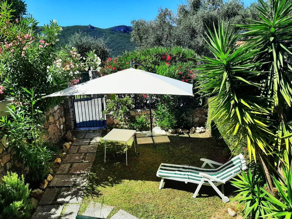um pátio com um guarda-sol branco, uma mesa e cadeiras em Casa Zila em Finale Ligure