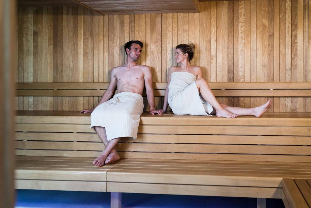a man and woman sitting in a sauna at Hotel Bohinj in Bohinj