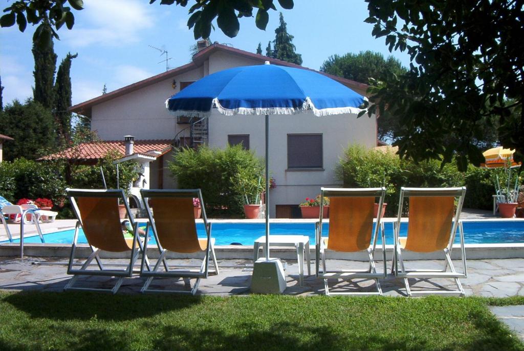 een groep stoelen en een parasol naast een zwembad bij Appartamento lussuoso 2 in Villa Riccardo Barga in Barga