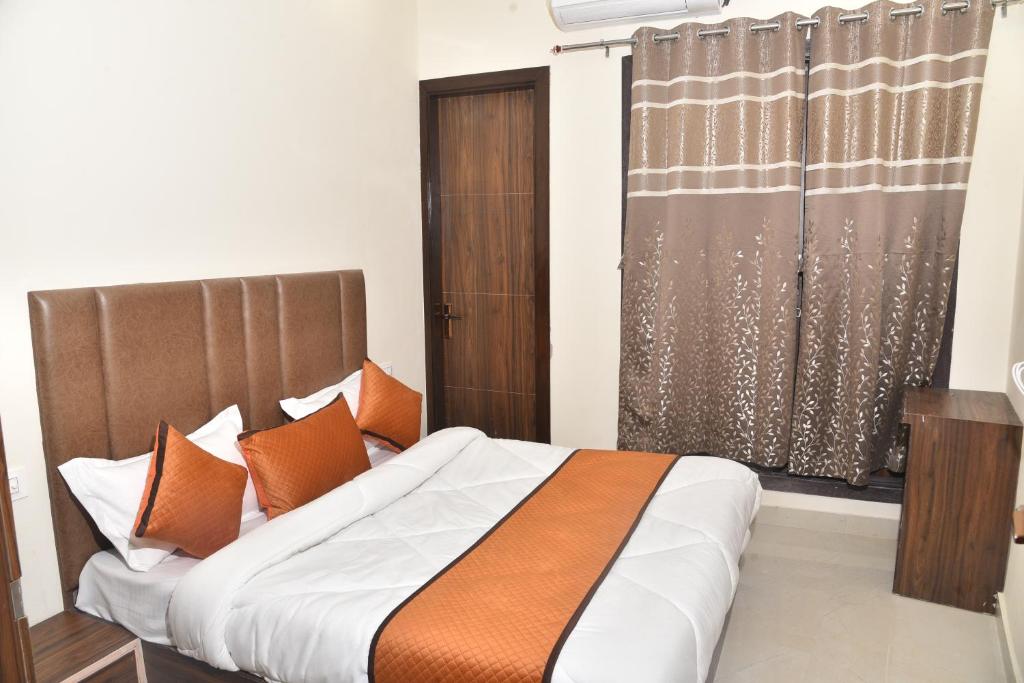 1 dormitorio con 1 cama con almohadas de color naranja y ventana en APEX HOTEL, en Amritsar