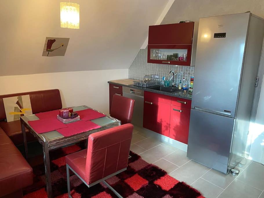 cocina con armarios rojos, mesa y nevera en Ferienwohnung in historischer Villa!, en Furth im Wald