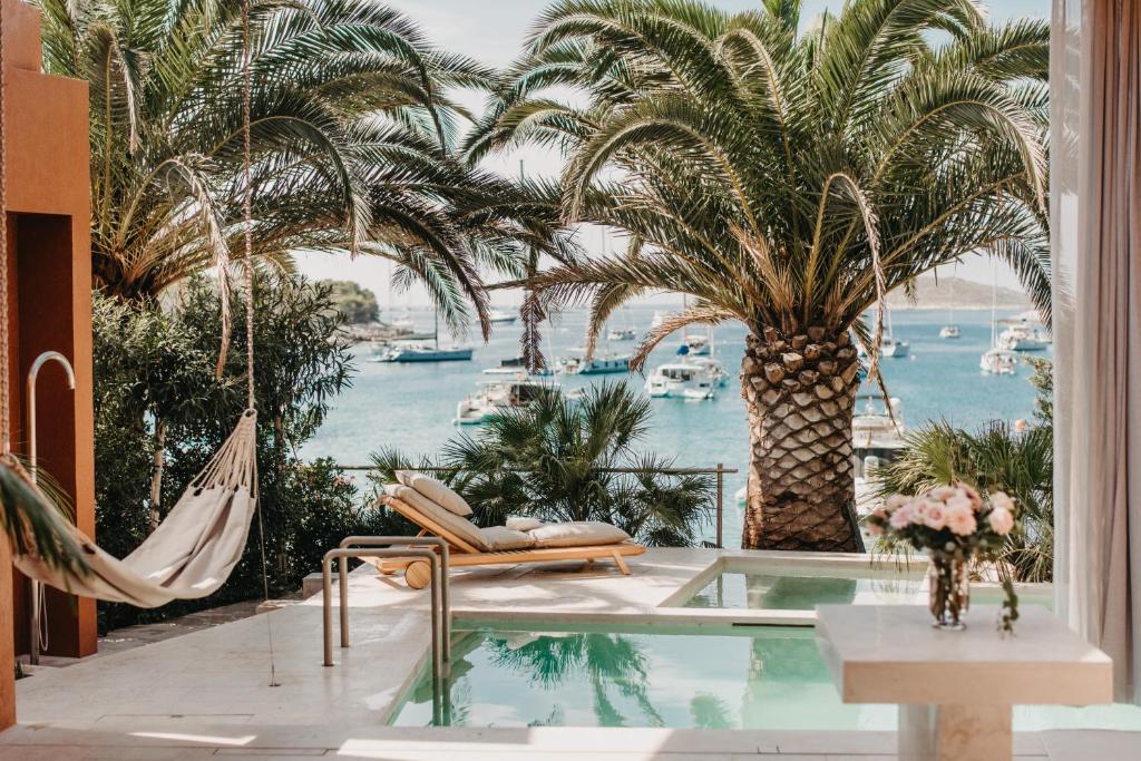 a room with a hammock and palm trees and a pool at Zori Timeless Hotel in Hvar