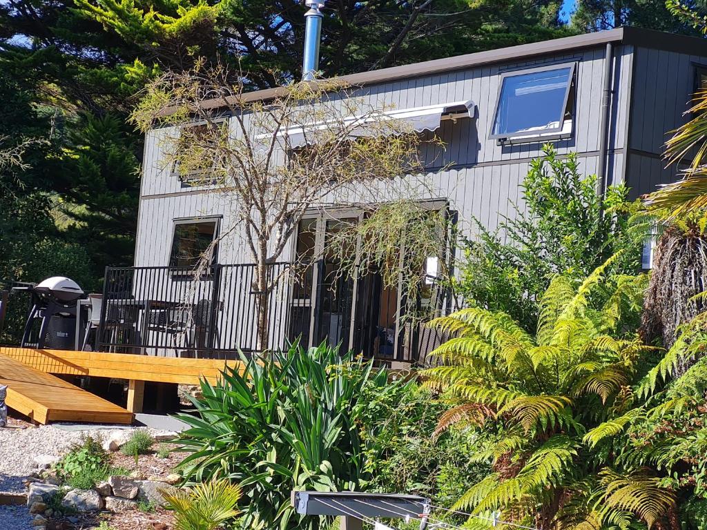 a house with a wooden bench in front of it at Kaiteriteri Tiny Home in Kaiteriteri