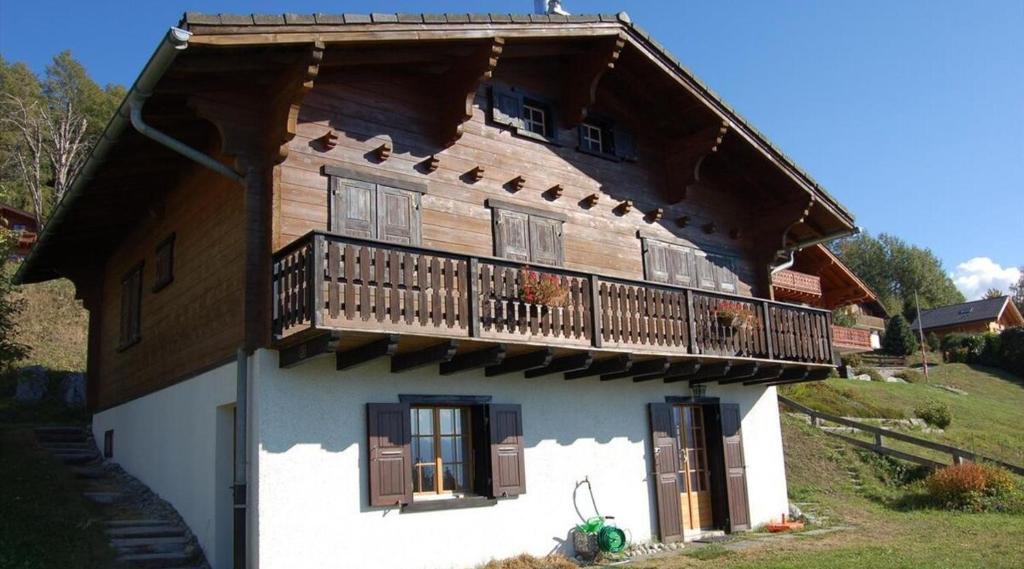 een houten huis met een balkon erboven bij Appartement dans un chalet avec jardin in Nax