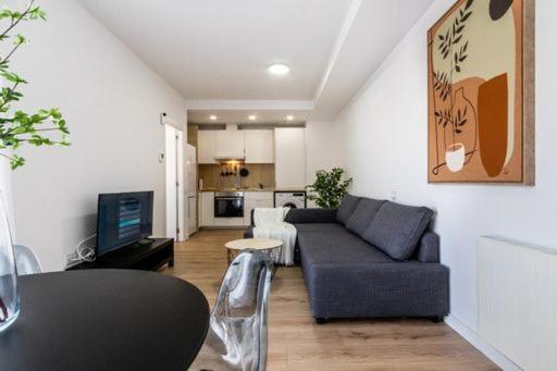 uma sala de estar com um sofá e uma cozinha em Acojedor y exclusivo loft by Lofties em Terrassa