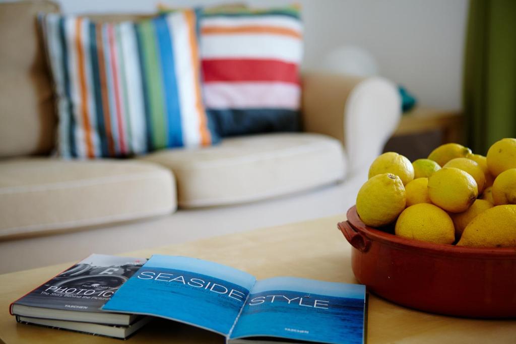 a bowl of lemons on a table next to a book at Amarandos Sea View Apartments in Vokaria