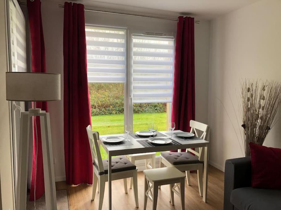 uma mesa de jantar e cadeiras num quarto com uma janela em Appartement F2 calme et élégant em Équemauville