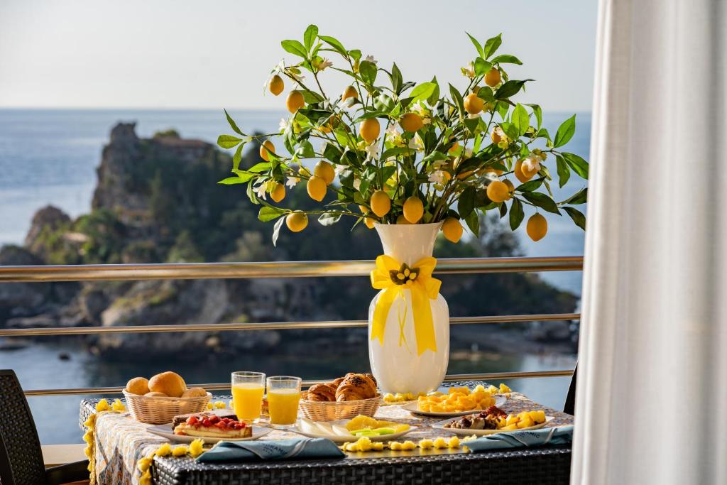 a table with breakfast foods and a vase of oranges at Taormina Panoramic Hotel in Taormina