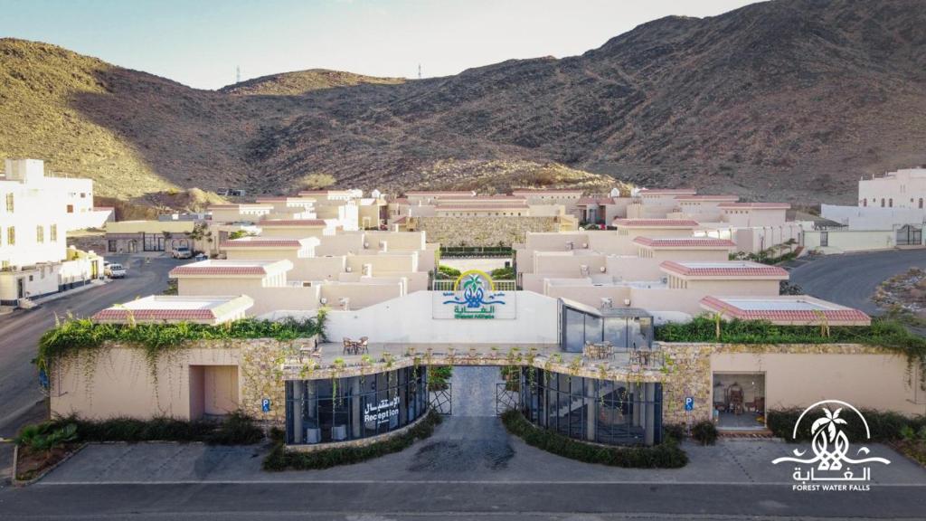 a group of buildings with mountains in the background at Shalalat Al Ghaba Chalets in Taif