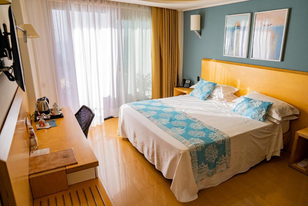a hotel room with a bed and a desk at Taormina Panoramic Hotel in Taormina