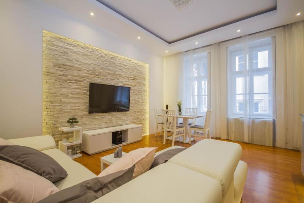 ein Wohnzimmer mit einem Sofa und einem TV an einer Backsteinwand in der Unterkunft Boutique Soho Apartment in Budapest