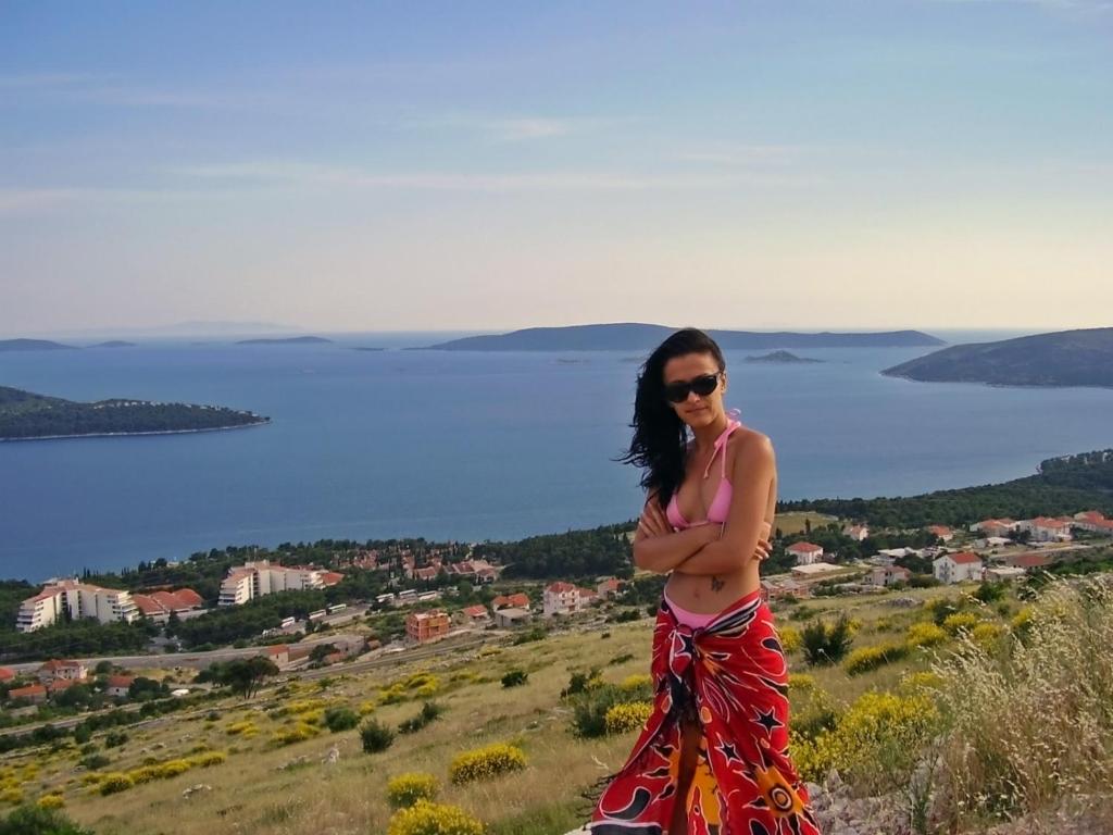 a woman standing on a hill with a view of the water at House Vranjica (608) in Seget Vranjica