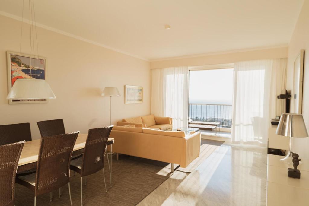 un salon avec un canapé et une table avec des chaises dans l'établissement EXCEPTIONNEL 4 pieces vue panoramique baie des anges proche plage, à Nice