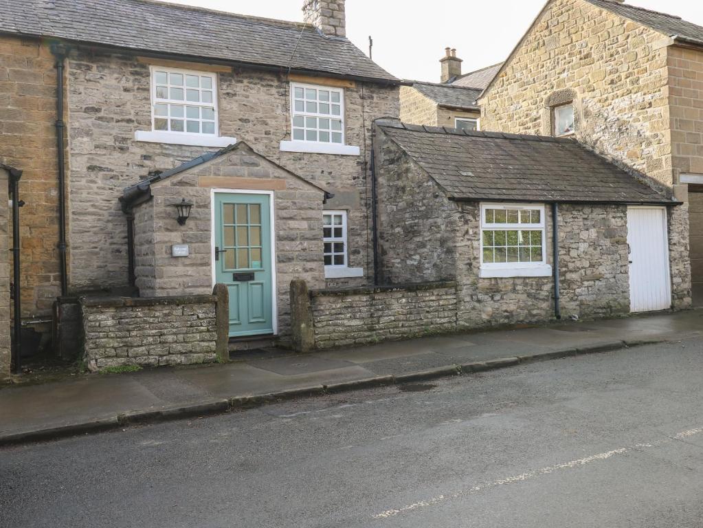 a brick house with a blue door on a street at Buttercup Cottage in Bakewell
