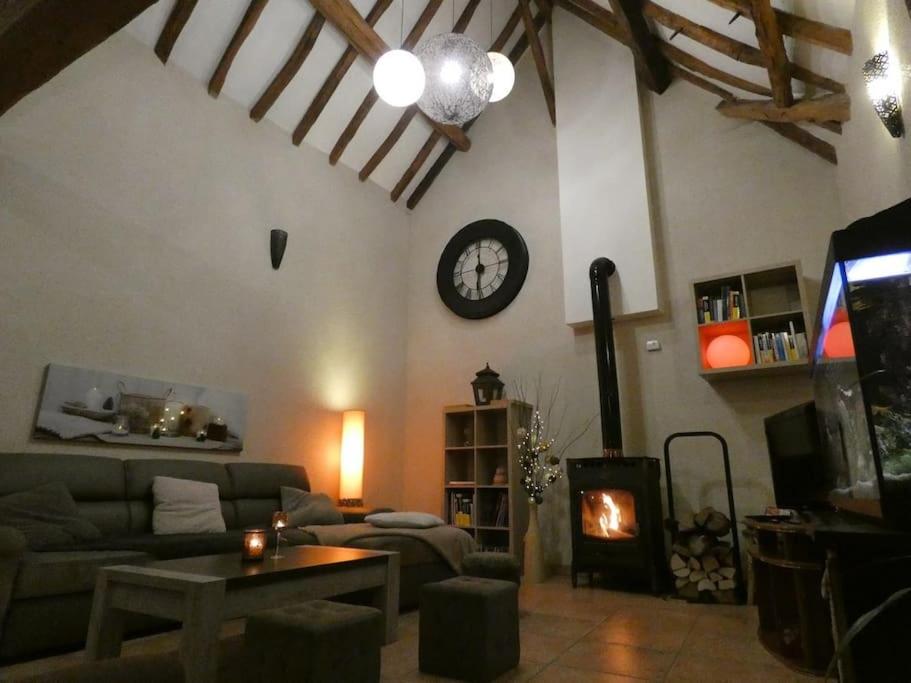 uma sala de estar com um sofá e um relógio na parede em Charming house - Beauval - Loire Valley em Saint-Cyran-du-Jambot