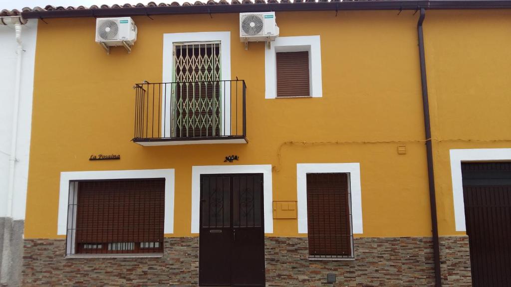 a yellow building with doors and a balcony at LA POSAINA in Serradilla