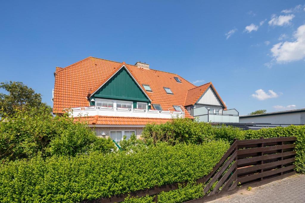 una casa con techo naranja sobre unos arbustos en Albatros en Norderney