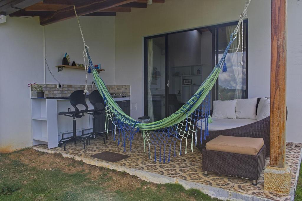 a hammock on a patio with a couch and a table at Villa Namaste, Cabaña Namaste 1 in Curití