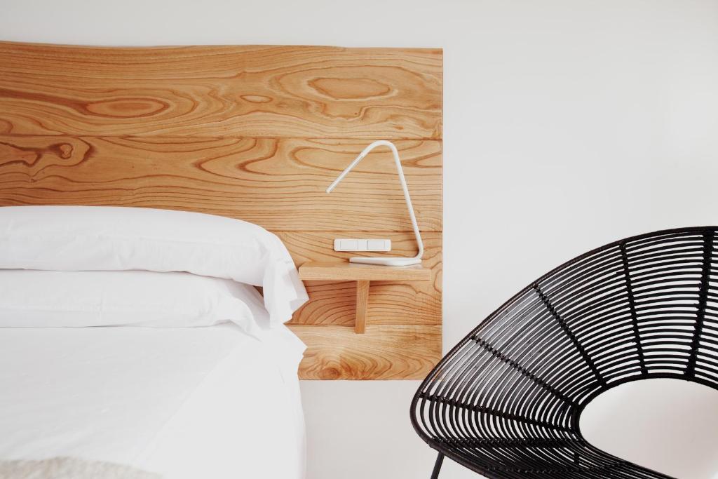 a bedroom with a white bed and a wooden wall at Hotel A Miranda in Feás