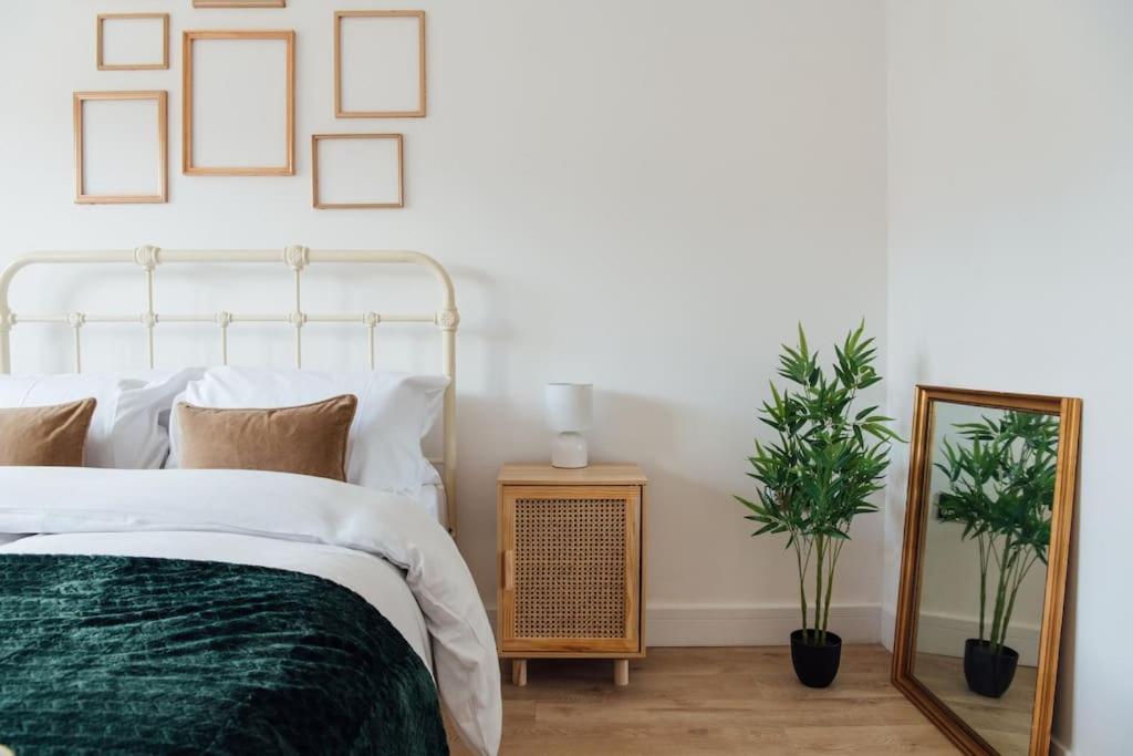 a bedroom with a bed and a mirror and plants at Cosy 2 Bedroom Flat in Ilford, London in Ilford