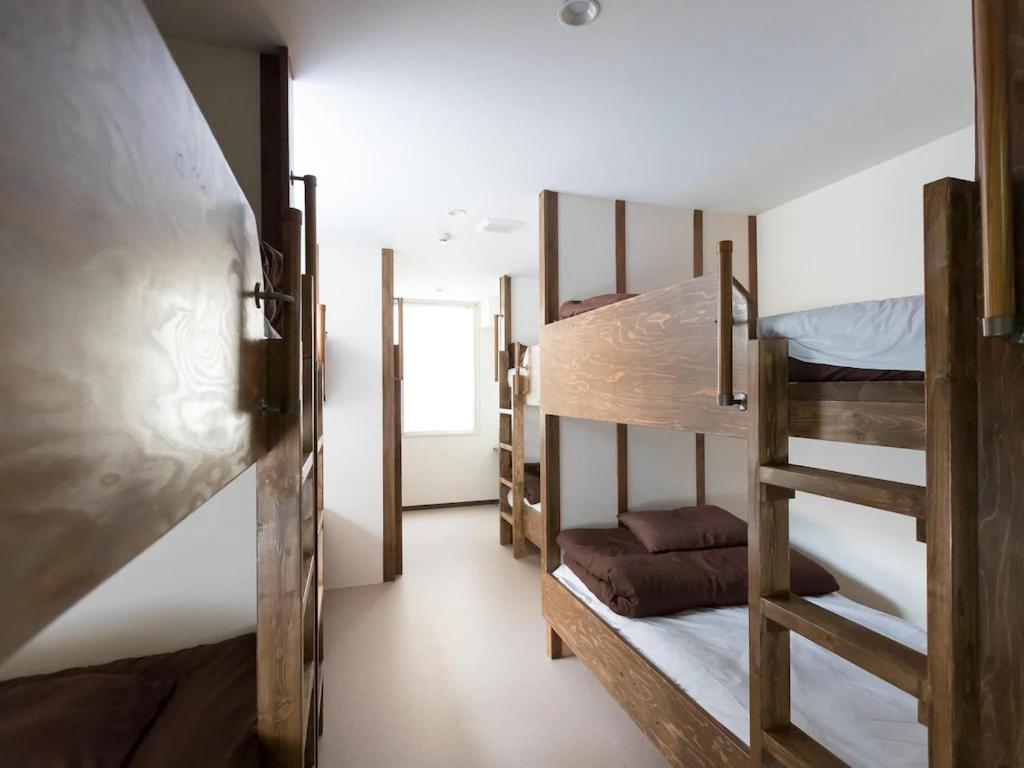 a room with three bunk beds and a hallway at Osaka Namba Hostel MIYABI in Osaka