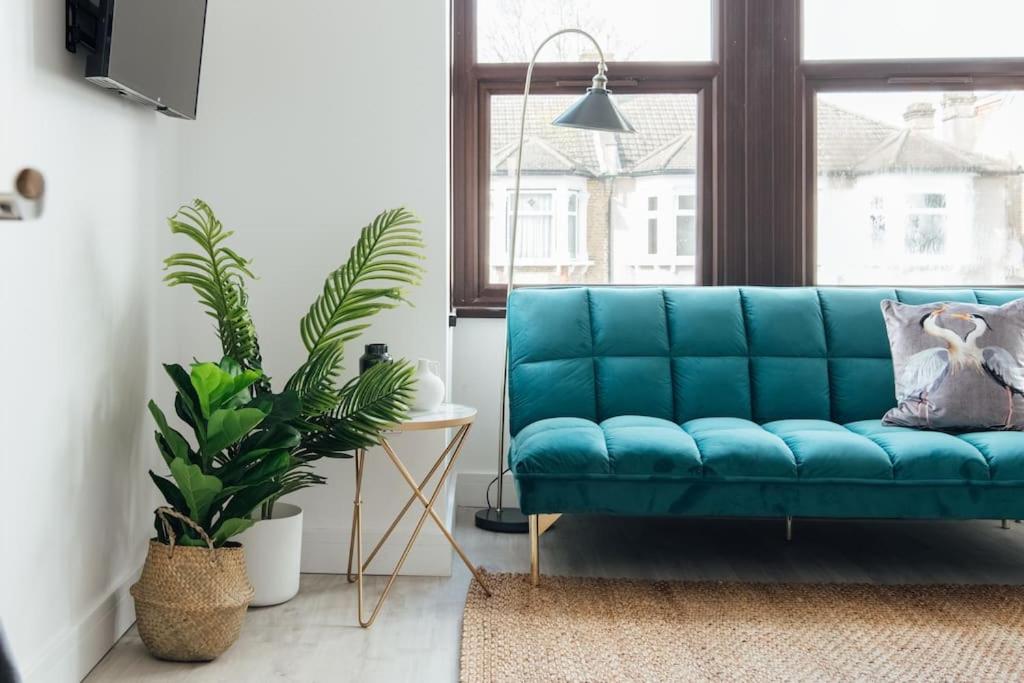 un sofá azul en una sala de estar con plantas en Modern 2 Bedroom Flat in Ilford, London en Ilford