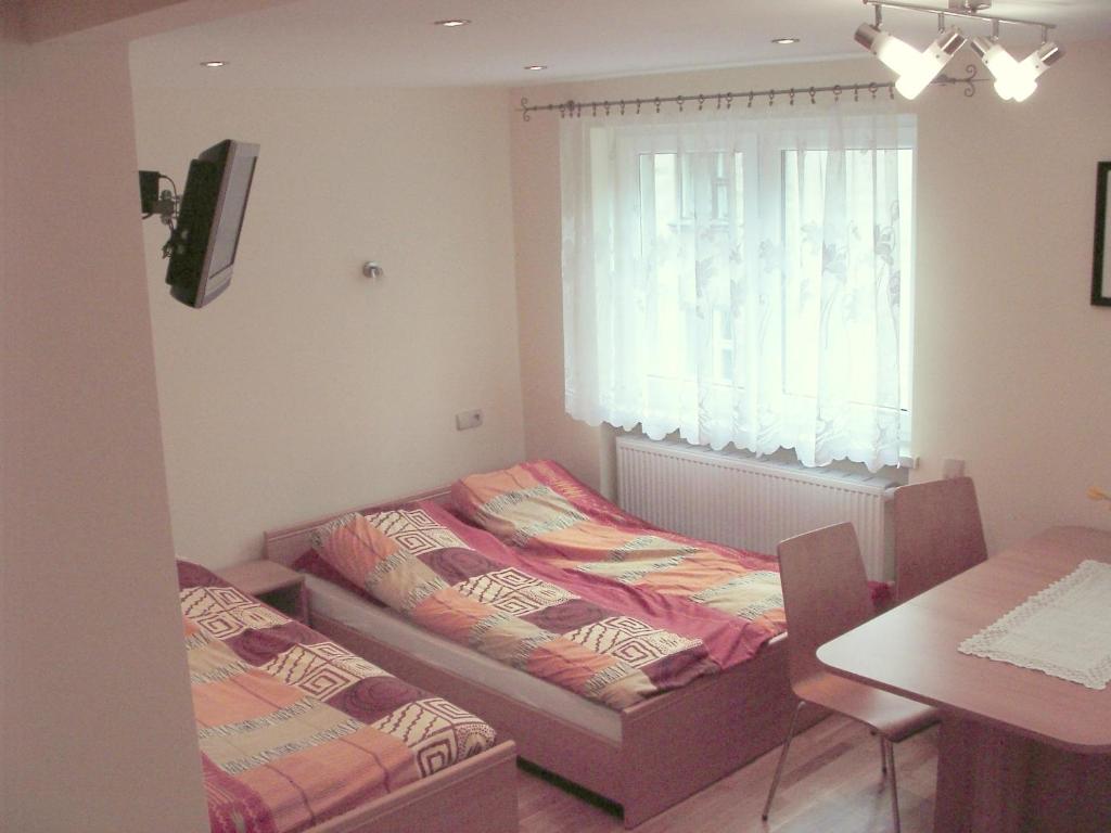 two beds in a room with a table and a window at Apartamenty Kubalonka in Istebna
