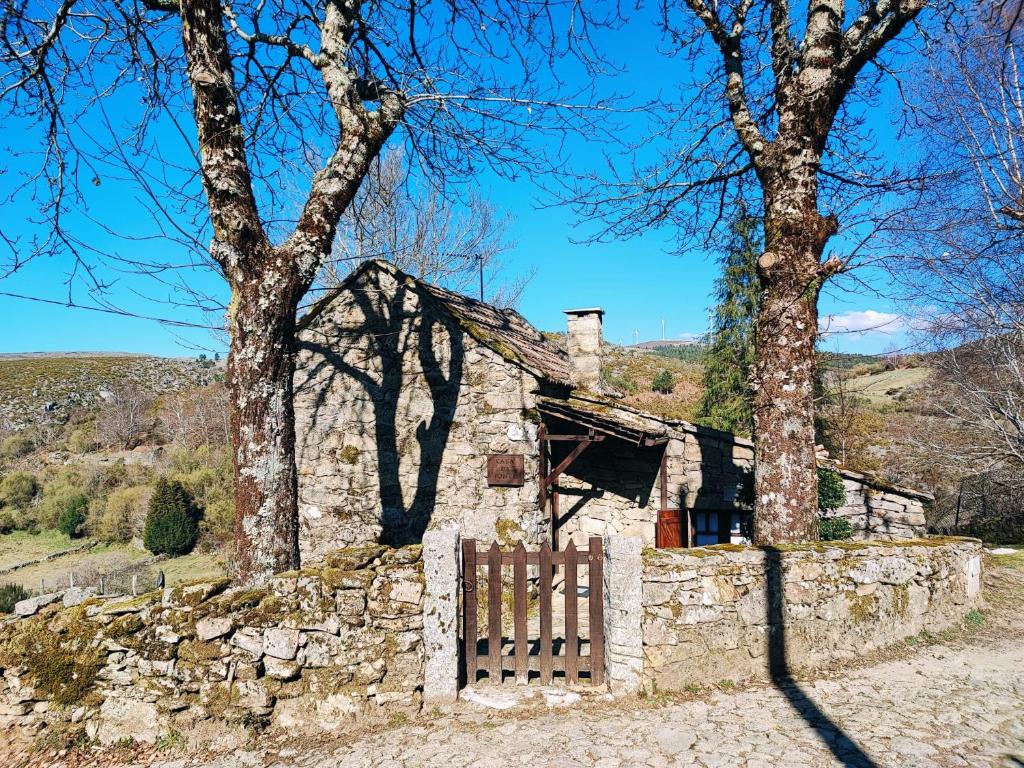 una antigua casa de piedra con una puerta y árboles en Casa da Fonte - Branda da Aveleira, en Melgaço