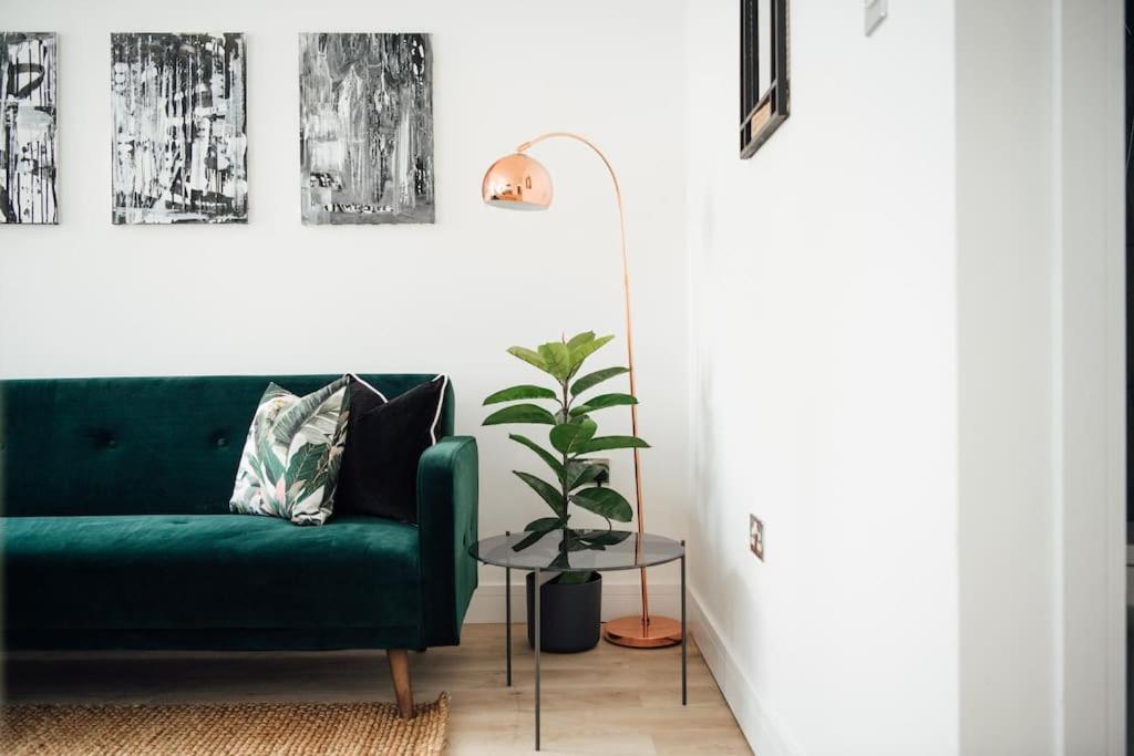 a green couch in a living room with a potted plant at Unique 2 Bedroom Flat in Ilford, London in Ilford