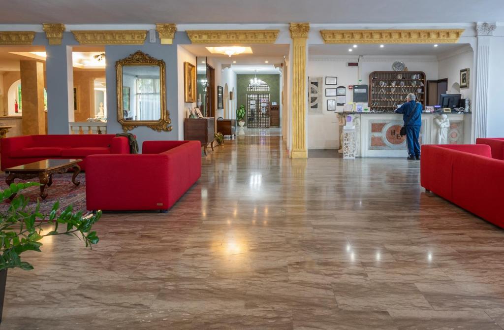 a man standing in a living room with red furniture at Hotel Terme Eden in Abano Terme
