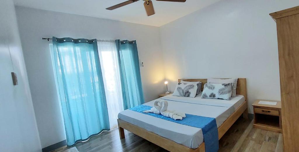 a bedroom with a large bed with blue curtains at Beyond Island in Moalboal
