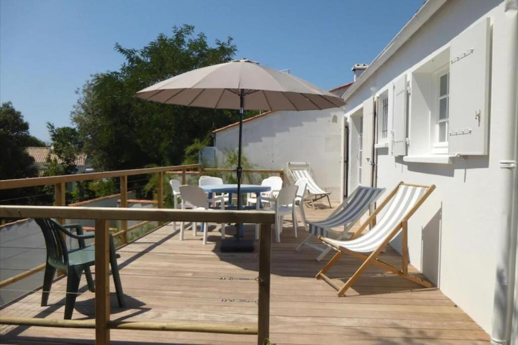 une terrasse avec une table, des chaises et un parasol dans l'établissement Maison Pimpino face à la plage, à Saint-Georges-dʼOléron
