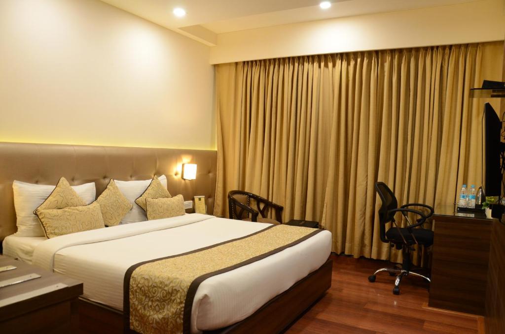 a hotel room with a bed and a desk at Hotel Ramaya in Gwalior