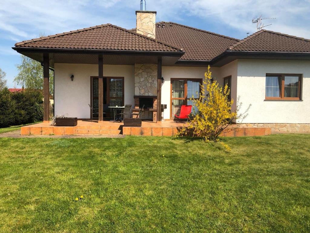 une maison blanche avec une terrasse couverte et une pelouse dans l'établissement Bungalow am Meer, à Grzybowo