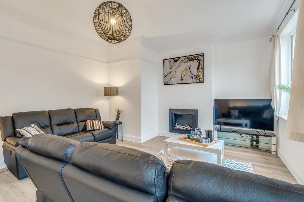a living room with two leather couches and a tv at Park House - Central spacious 4 bedroom Edwardian house, with games room in the heart of Plymouth in Plymouth