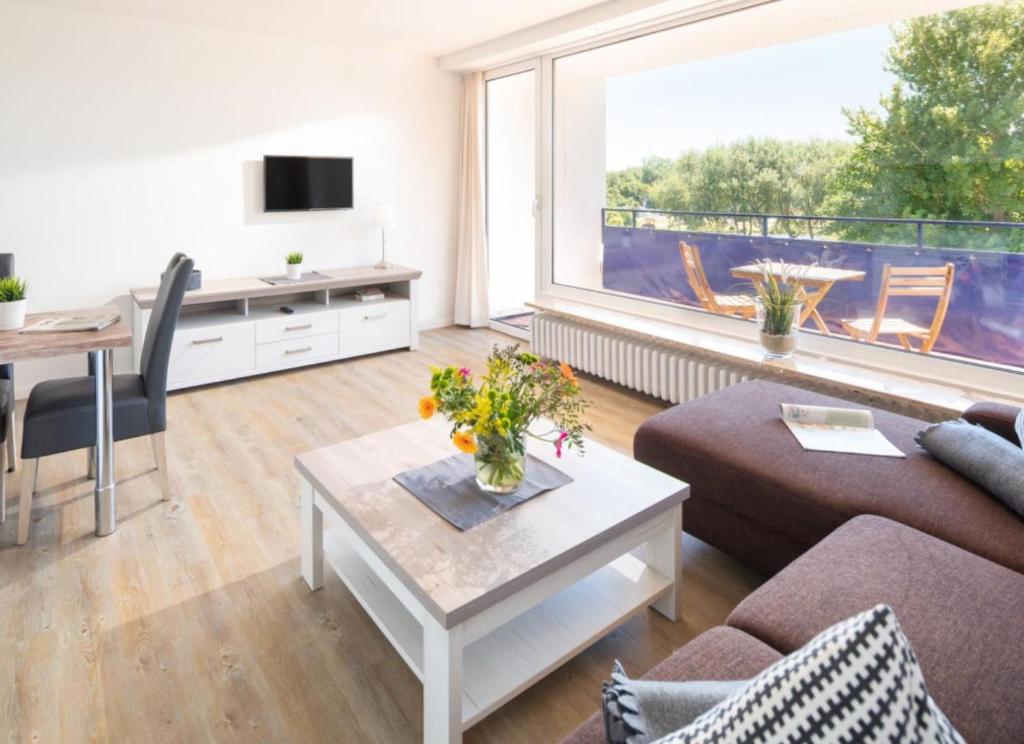 uma sala de estar com um sofá, uma mesa e uma grande janela em weitSicht em Norderney