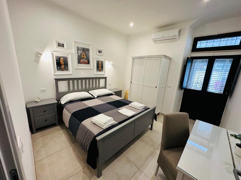 a bedroom with a bed and a desk and a chair at Tannur Del Carmine in Noto
