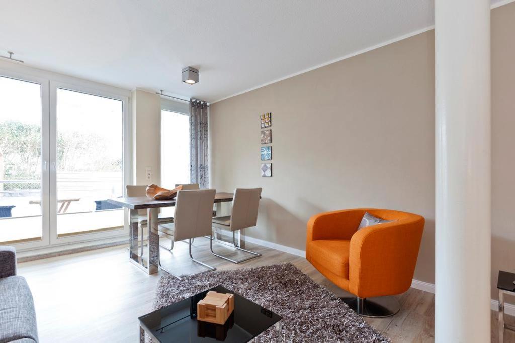 ein Wohnzimmer mit einem orangenen Stuhl und einem Tisch in der Unterkunft Sonne 3 in Norderney