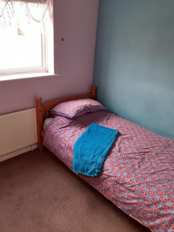 a bed with a blue comforter in a bedroom at Home from home, single room with virgin channels, Wifi & free parking in Poole