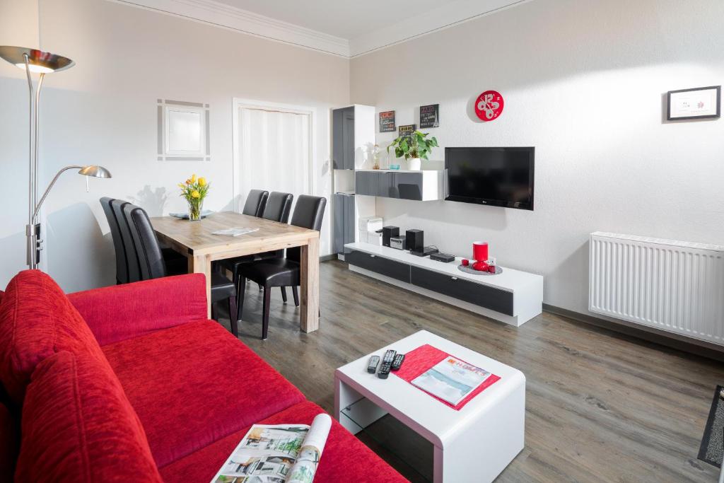 Una sala de estar con un sofá rojo y una mesa. en Villa Stefanie 2, en Norderney