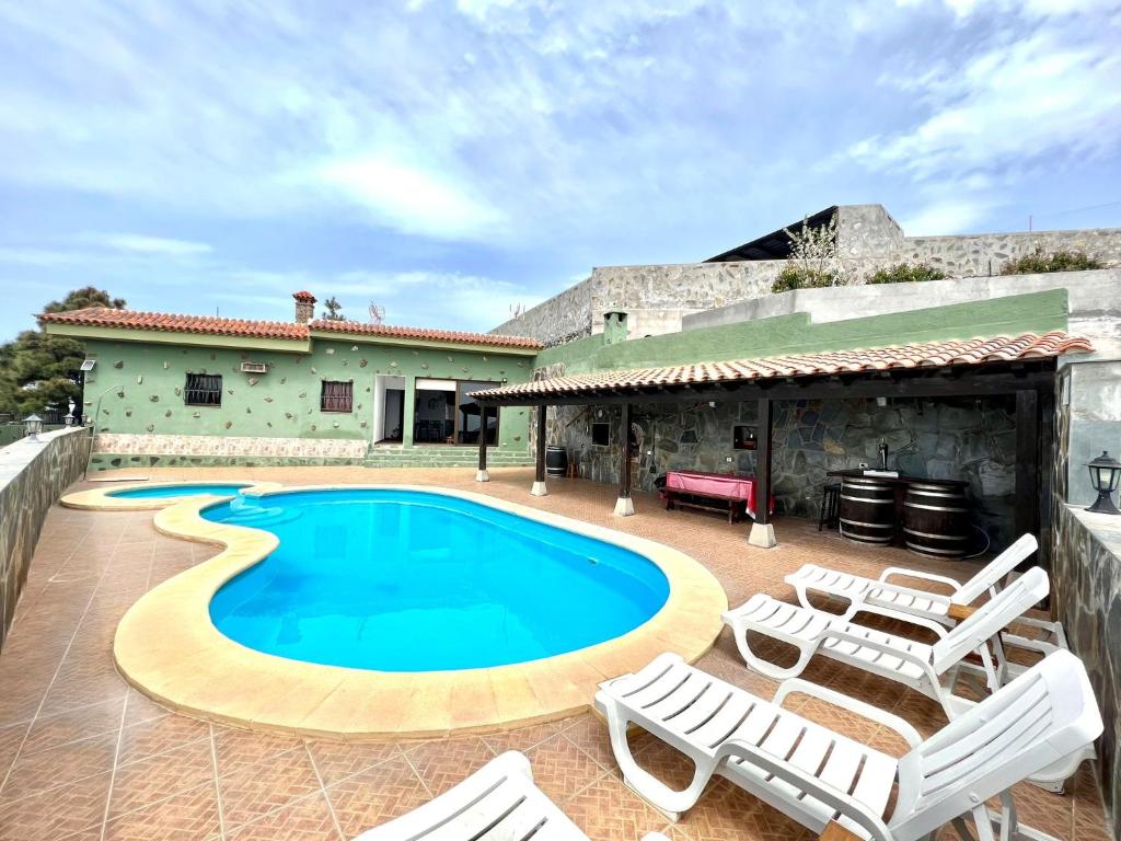 a swimming pool with lounge chairs and a house at Villa with private pool and great view of the Atlantic Ocean in Adeje