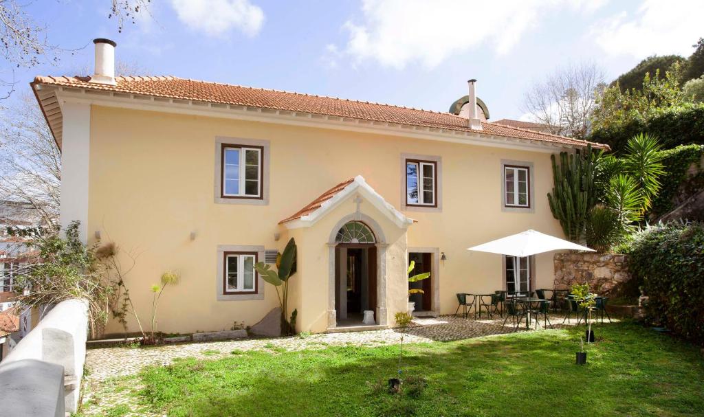 a yellow house with a table and an umbrella at Palácio de Sintra Boutique House in Sintra