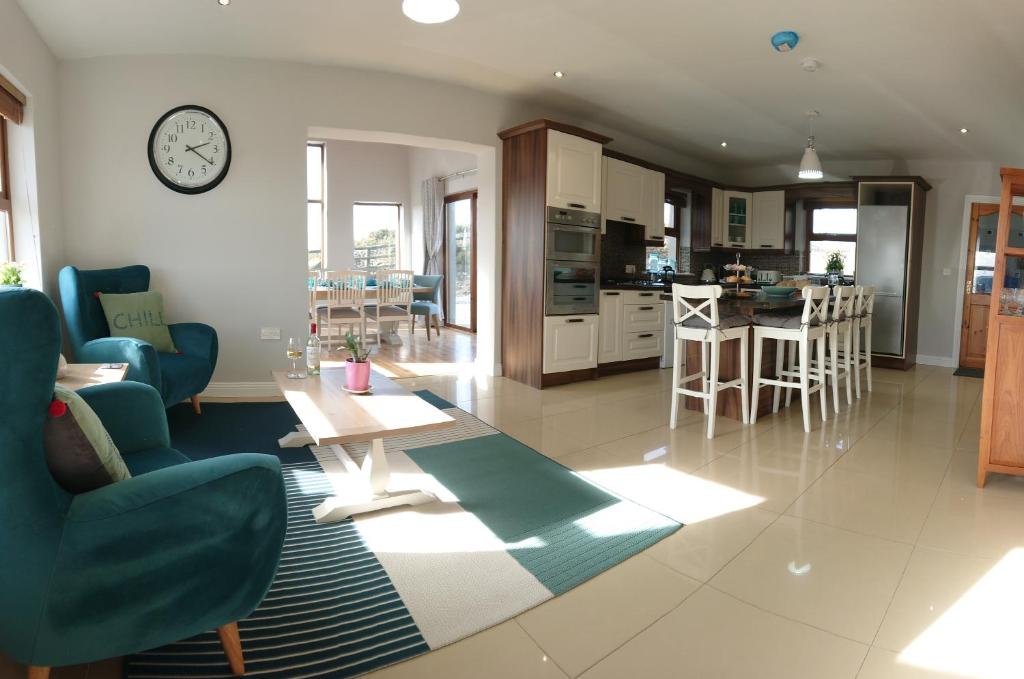 a living room and kitchen with a clock on the wall at Melroche House Doolin in Doolin