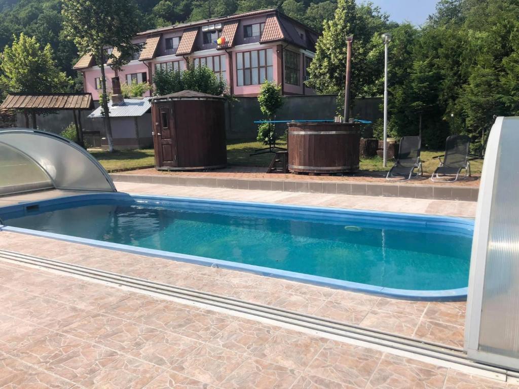 a swimming pool in front of a house at Pensiunea Oșencuța in Talmesch