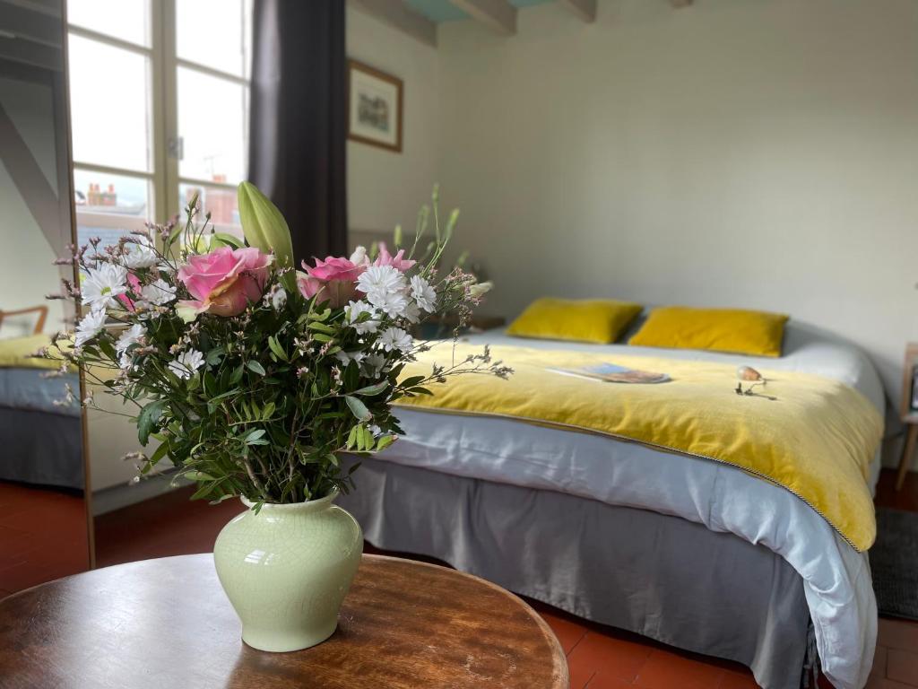 Chambres chez l'habitant Capucine في أونفلور: مزهرية مع الزهور على طاولة في غرفة النوم