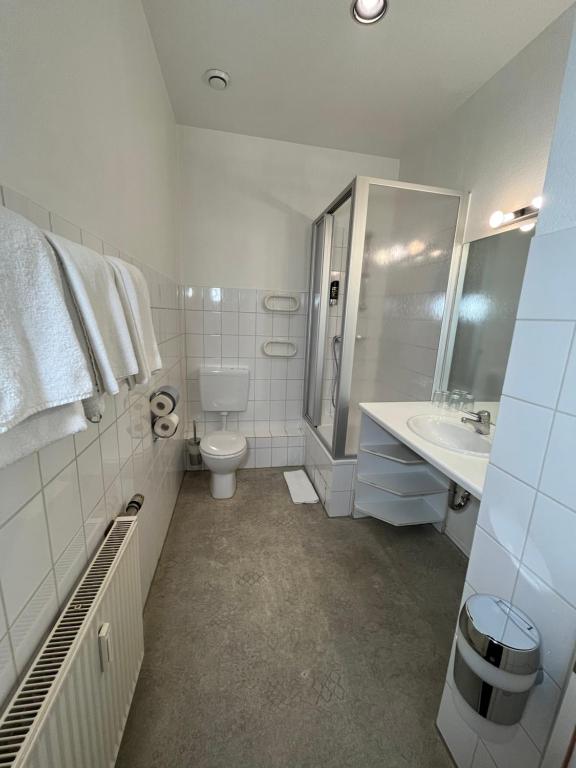 a white bathroom with a toilet and a sink at Hotel Schwarzer Bär in Hannover