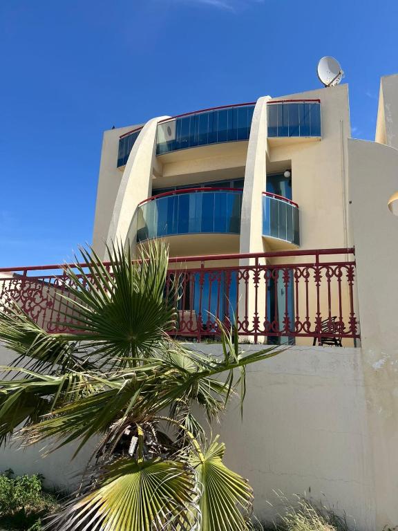 ein Gebäude mit einem Balkon und einer Palme in der Unterkunft 5 bedroom relaxing villa with sea view in Umm al-Qaiwain