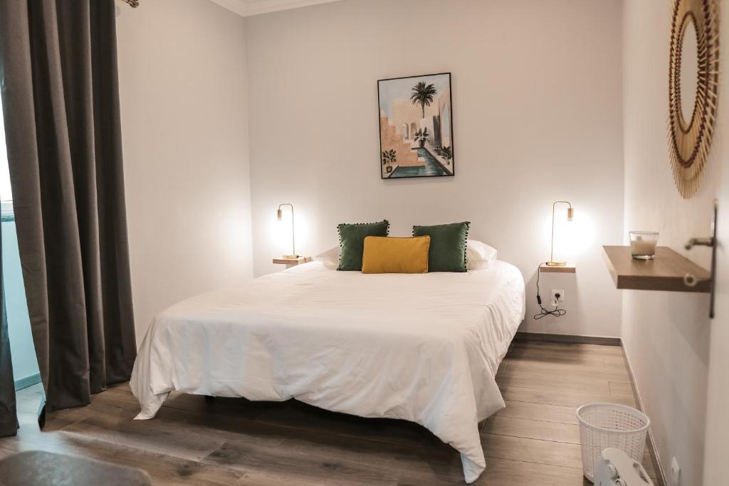 1 dormitorio con 1 cama blanca grande con almohadas verdes y amarillas en Casa Maresia en Fenais da Luz