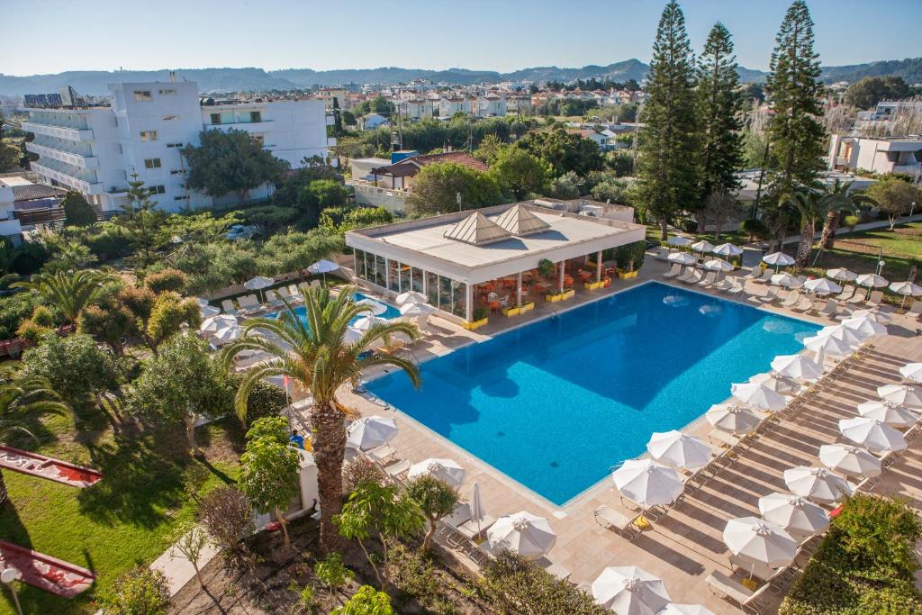 una vista aérea de una piscina con sillas y un edificio en IALYSSOS BAY HOTEL, en Ialisos